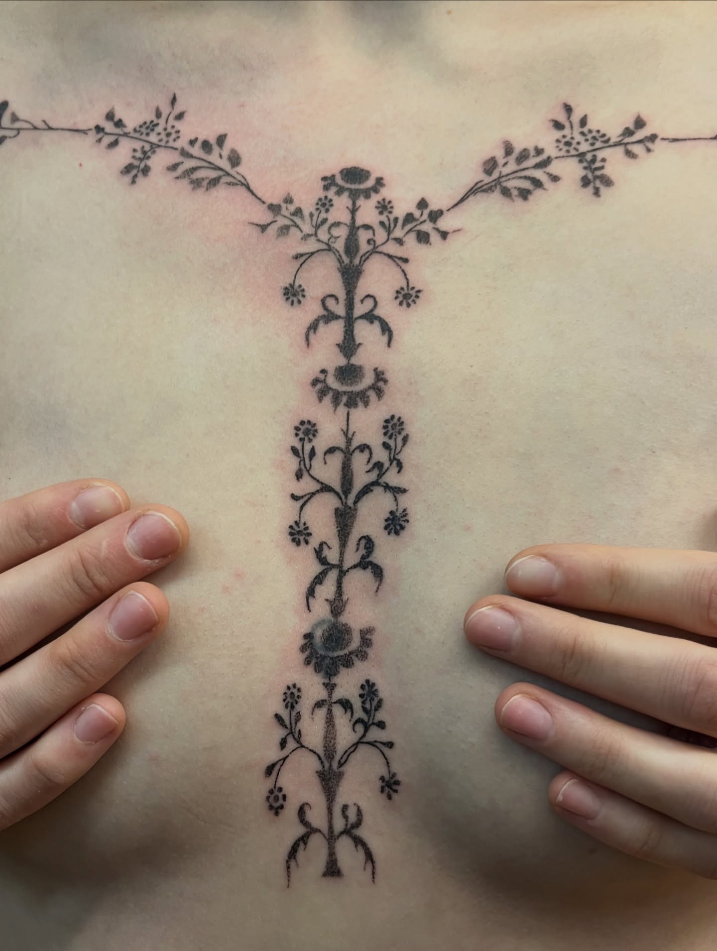 Tatouage handpoke ornemental sur le sternum, motifs floraux