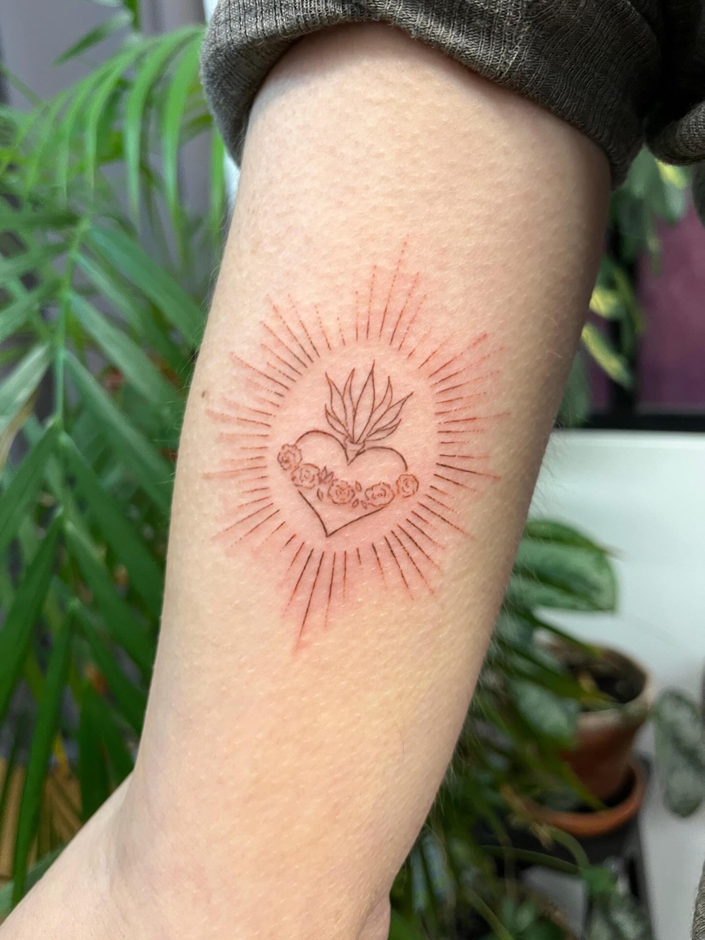 Tatouage handpoke cœur sacré sur l'avant-bras, encre rouge