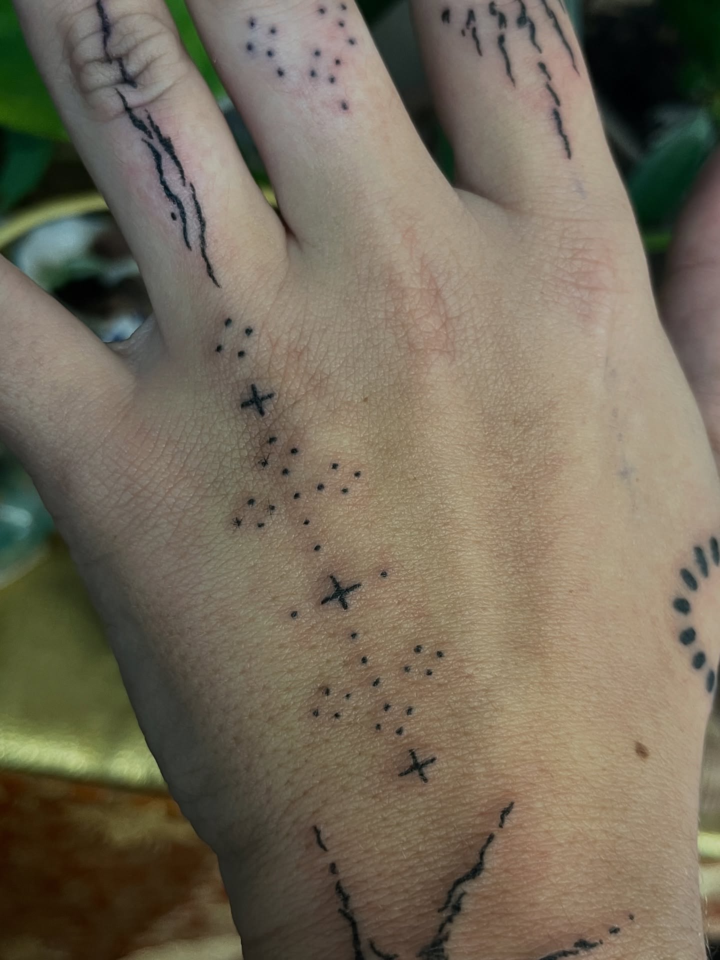 Tatouage handpoke symbolique sur la main, croix et points
